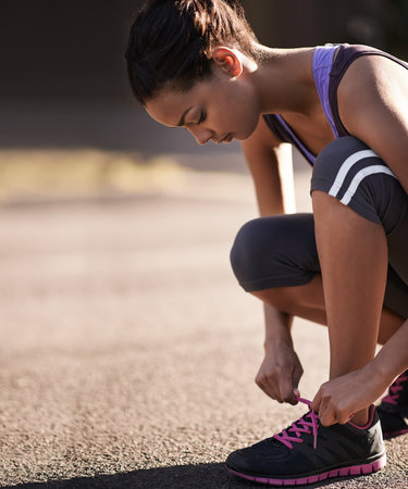 Life is better in running shoes. a runner tying her shoelaces before a run.の写真素材