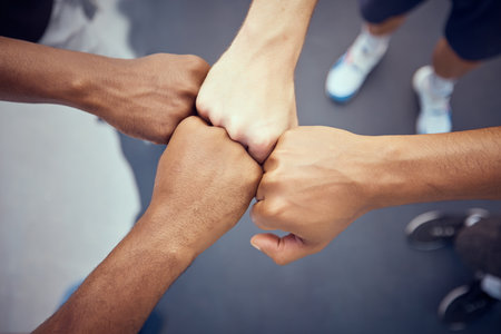 Teamwork, hands and collaboration with people standing in a circle or huddle in support, unity or solidarity. Team, group of community with fists joined in union together from above and closeupの写真素材