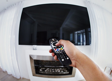 Get ready to be entertained. POV shot of a person aiming a remote control at a flat screen...
