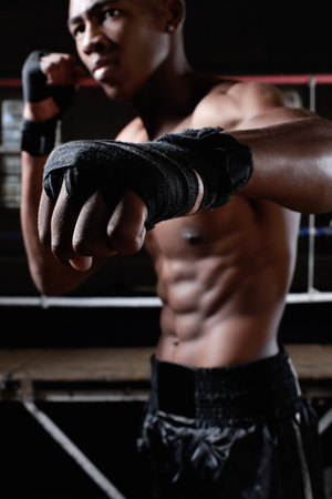 Punching athlete. African American athletic man with wrapped fists punches.