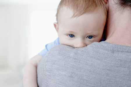 Feeling sleepy. Closeup of a sleepy baby boy lying on his mothers shoulder.の写真素材