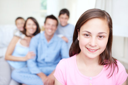 Shell always have her family for support. Portrait of an adorable little girl smiling happily while her family sits blurred in the background - Copyspace.の写真素材