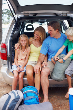 Young girl sitting in the back of a car with family. Portrait of young girl sitting in the back of a car with family looking at her.の写真素材