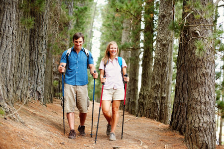 Couple on a hike. Full length of couple with backpack walking with hiking poles.の写真素材