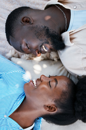 Love, happiness and black couple laying outdoors on the floor with blankets to relax in a park....