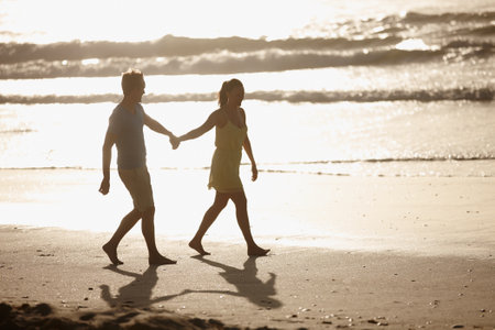 They enjoy long walks on the beach. an affectionate couple walking on the beach.の写真素材