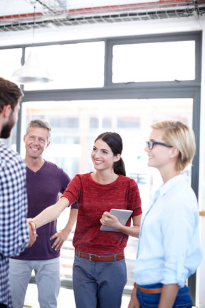 Welcoming her to the company. two coworkers shaking hands.