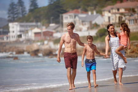Enjoying the beach together. a family walking along the beach.の写真素材