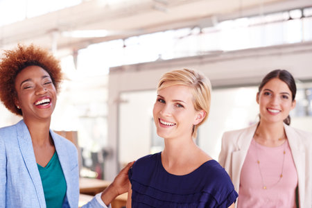 The real secret of success is enthusiasm. Portrait of three female coworkers standing in an office.の写真素材
