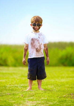 A muddy superhero. A little boy dressed as a superhero and covered in mud.