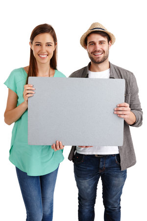 This is a message from us. Studio portrait of a smiling young couple holding up a blank poster.