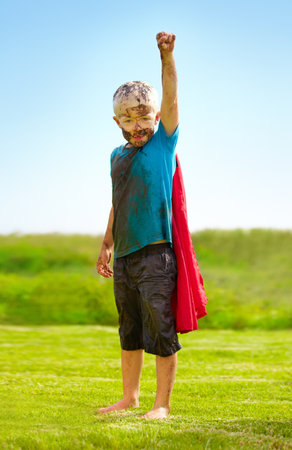 A muddy superhero. A little boy dressed as a superhero and covered in mud.の写真素材