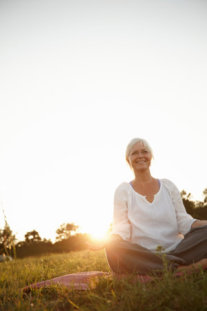Making time to meditate. an attractive mature woman doing yoga in nature.の写真素材