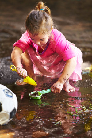 Childhood is all about getting dirty. a little girl playing outside in the mud.の写真素材