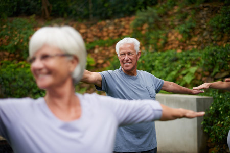 Maintaining my balanced life. a senior man enjoying an outdoor yoga class.の写真素材
