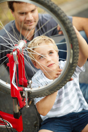 A new learnt skill he wont forget. Young father teaching his son how to change a bike puncture.の写真素材