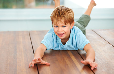 Having fun at home. A cute young boy playing on the dinner table at home.の写真素材