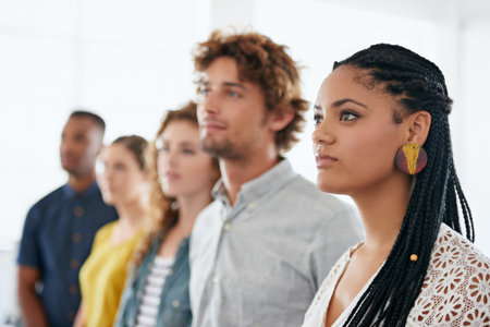 Young and ambitious. a beautiful young woman standing with her colleagues against a white background.の写真素材