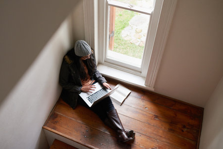 Her own quiet corner to study. A young woman using her laptop at home.の写真素材