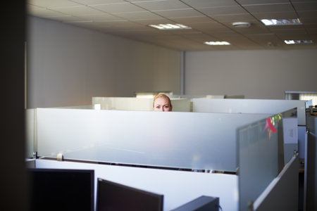 Putting in some extra hours. Portrait of an attractive young woman standing in her office cubicle.の写真素材