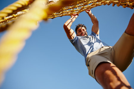 Catch me if you can. a young man gripping a rope wall at bootcamp.の写真素材