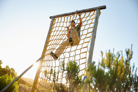 Tough situations build strong people. a man climbing over an obstacle at bootcamp.の写真素材