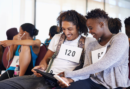 Having a lighthearted moment before their audition. two dancers using their digital devices while...