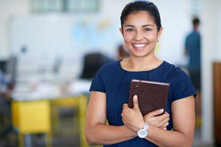 Ive always got my schedule handy. Portrait of an attractive young businesswoman holding her journal while standing in an office.の写真素材