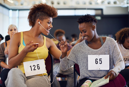 They love music and dance. two female dancers listening to music while waiting for a dance audition.