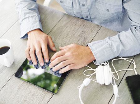 Doing some web browsing outdoors. Cropped view of a mans hands using a digital tablet while sitting...