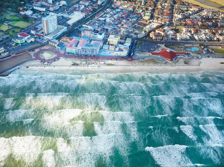 Seaside town. Aerial shot of ocean waves and a small seaside town.の写真素材