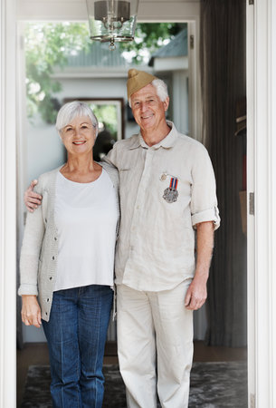 Proud patriots. A happy senior man standing with his wife wearing his old army uniform - portrait.の写真素材