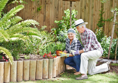 Gardening is the best way to stay young. A happy senior couple busy gardening in their back yard.の写真素材