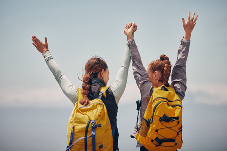 Women outdoor travel, celebrate success adventure and hiking support achievement on mountain top. Blue sky landscape, best friends love nature, sunshine at peak and calm freedom of girl sisters tripの写真素材