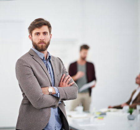 The boardroom is where I belong. Portrait of a young businessperson in a conference room with colleagues in the background.の写真素材