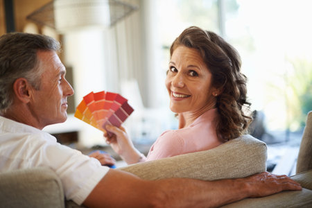 Holding a vibrant color palette. A mature couple looking over paint swatches together at home.の写真素材