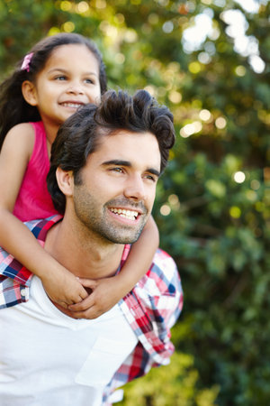 Hes an exceptional father. A handsome young father piggybacking his cute young daughter.の写真素材