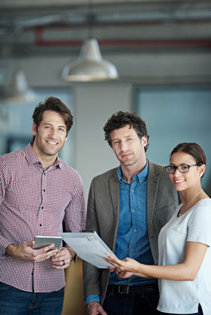 Meeting of great corporate minds. Portrait of a group of coworkers standing in an office.の写真素材