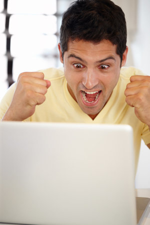 Winning isnt everything, its the only thing. an attractive young man watching his laptop screen.の写真素材