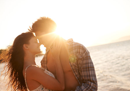 Kisses at sunset. a young couple enjoying a beach getaway.の写真素材