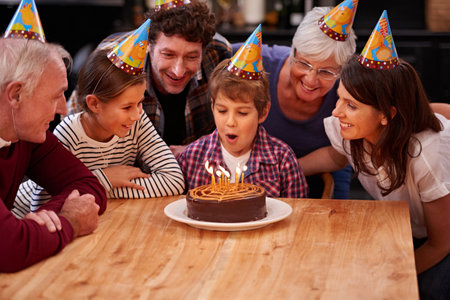 I can blow them out at once. a happy young boy celebrating his birthday with his family.の写真素材