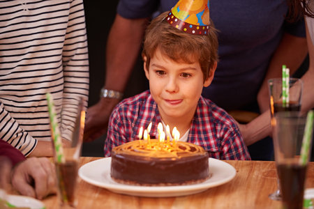 Did someone say cake. a young boy getting ready to blow out the candles on his birthday cake.