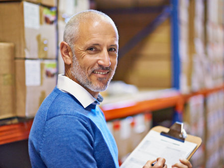 Im on it. A warehouse employee standing with a clipboard beside shelving filled with boxes.の写真素材