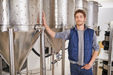 These tanks a holding the finest of beers. Portrait of a man working in a microbrewery.