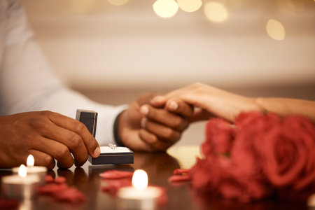 Ring, hands and engagement with a couple on a date and getting engaged as fiance by candlelight. Love, question and marriage with a proposal between a man and woman in a restaurant for romanceの写真素材