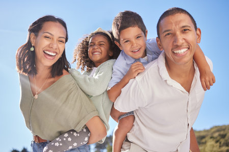 Happy family portrait, parents piggyback children and smile together at outdoor park in blue sky...