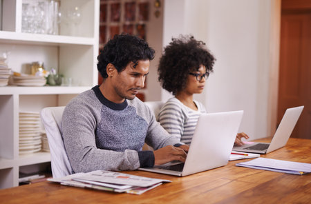 Home admin made easy. a young couple busy on their laptops at home.
