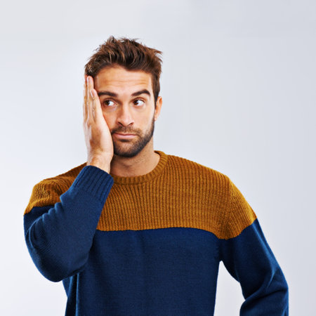 My bad. Studio shot of a young man looking regretful against a gray background.の写真素材