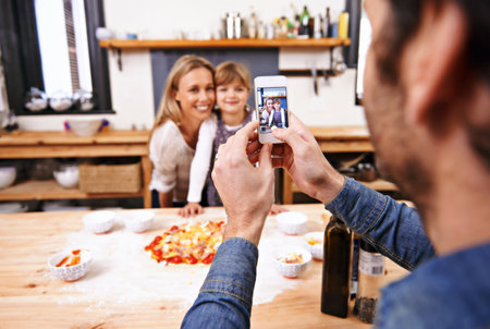 Say Pizza. A dad taking a photo of his family making homemade pizza.の写真素材