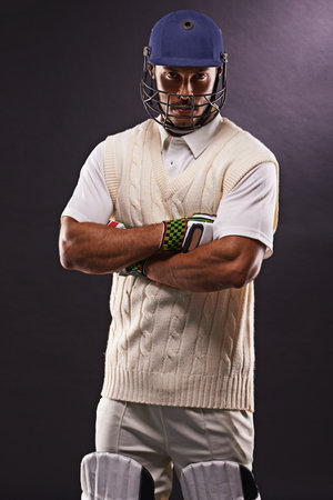 Lets hit the pitch. A cropped shot of an ethnic young man in cricket attire isolated on black.の写真素材